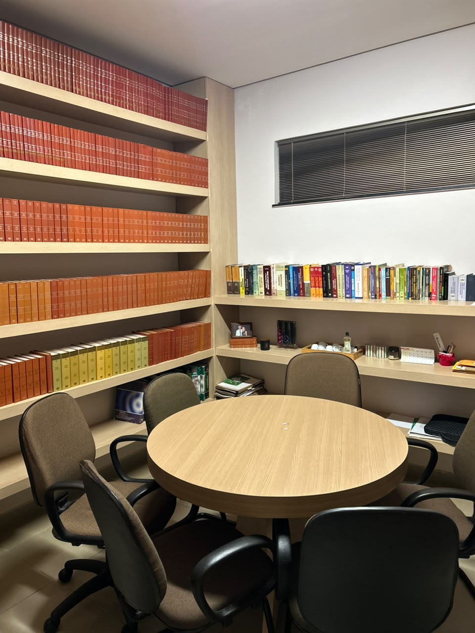 Sala de reunião com mesa redonda e estante de obras jurídicas