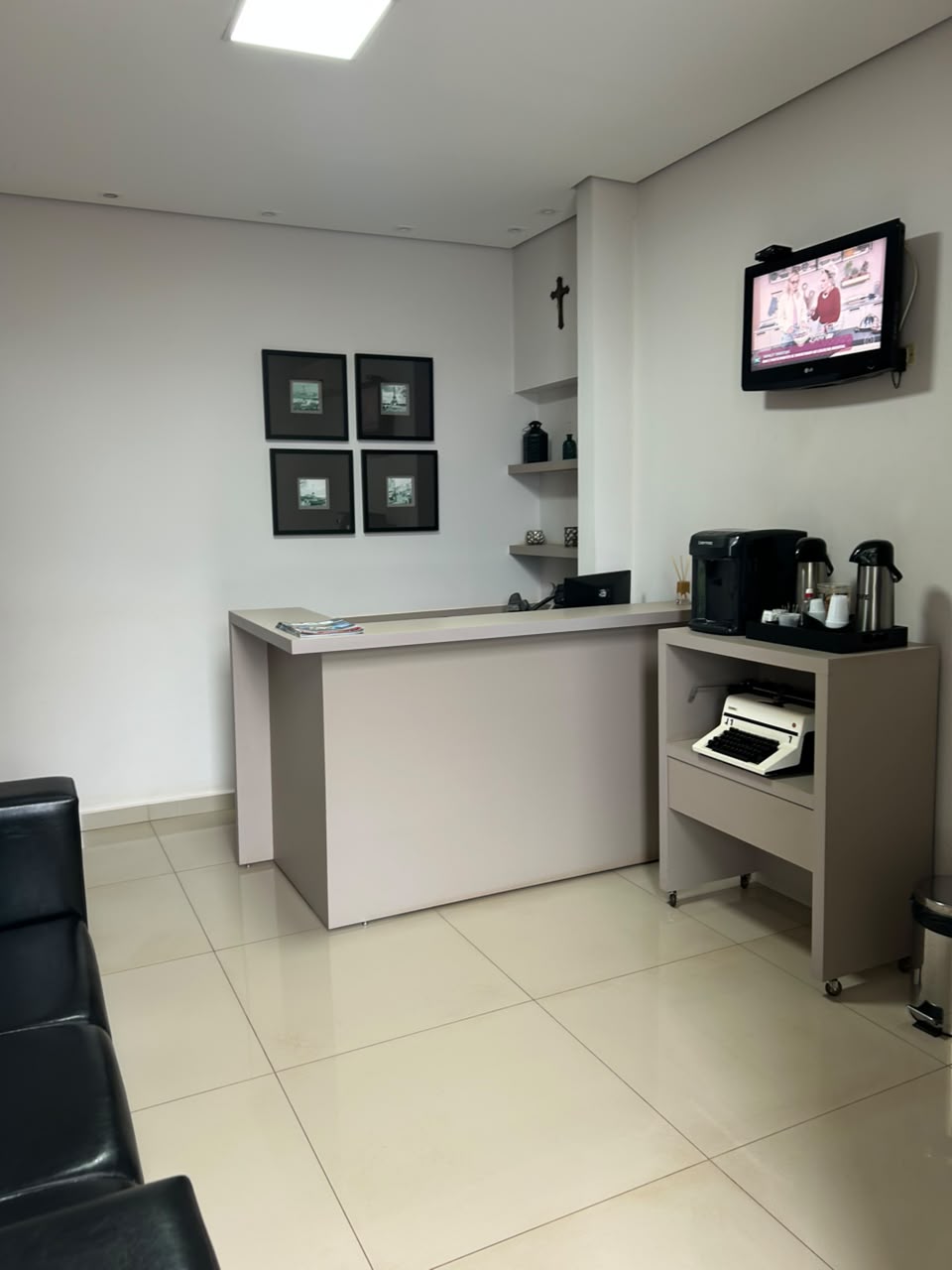 Área de atendimento com estação de café e quadros na parede