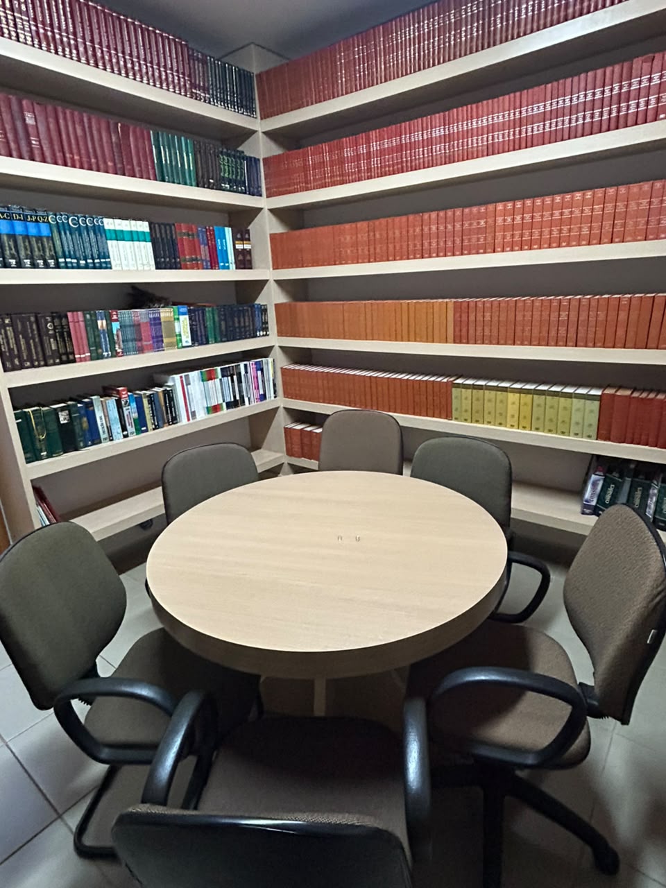 Sala de reunião com mesa redonda e biblioteca jurídica