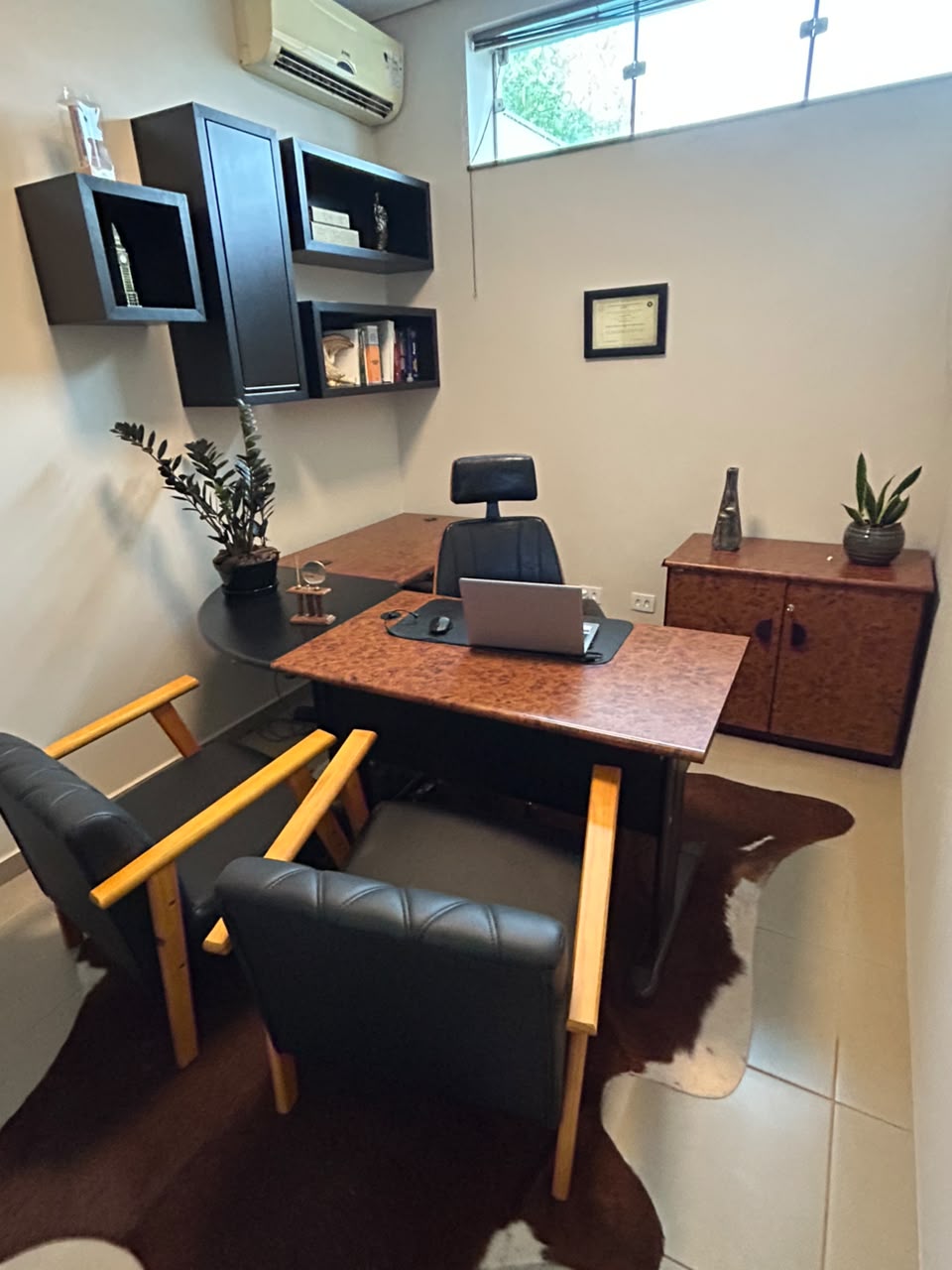 Mesa de atendimento com cadeiras de couro e prateleiras